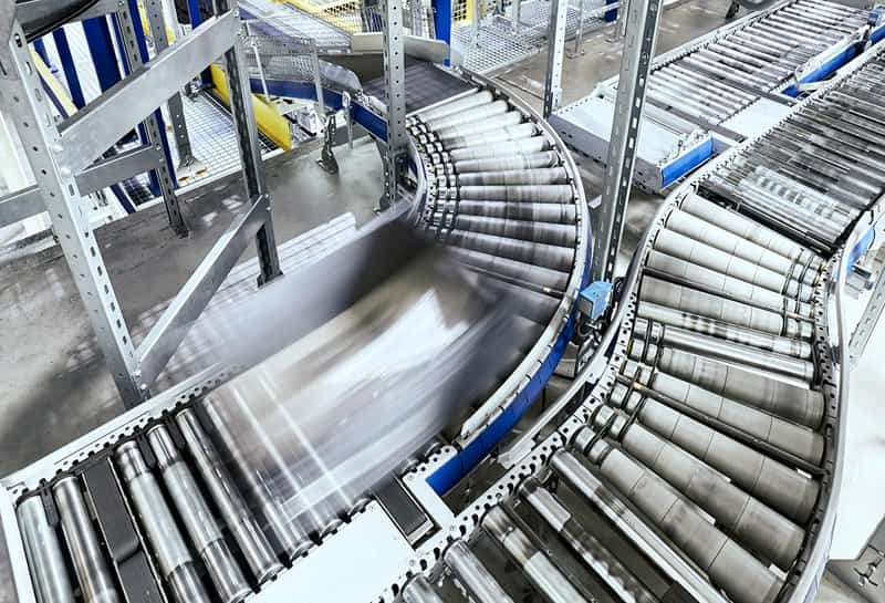 Industrial roller conveyor system transporting materials through automated material handling process in a manufacturing facility